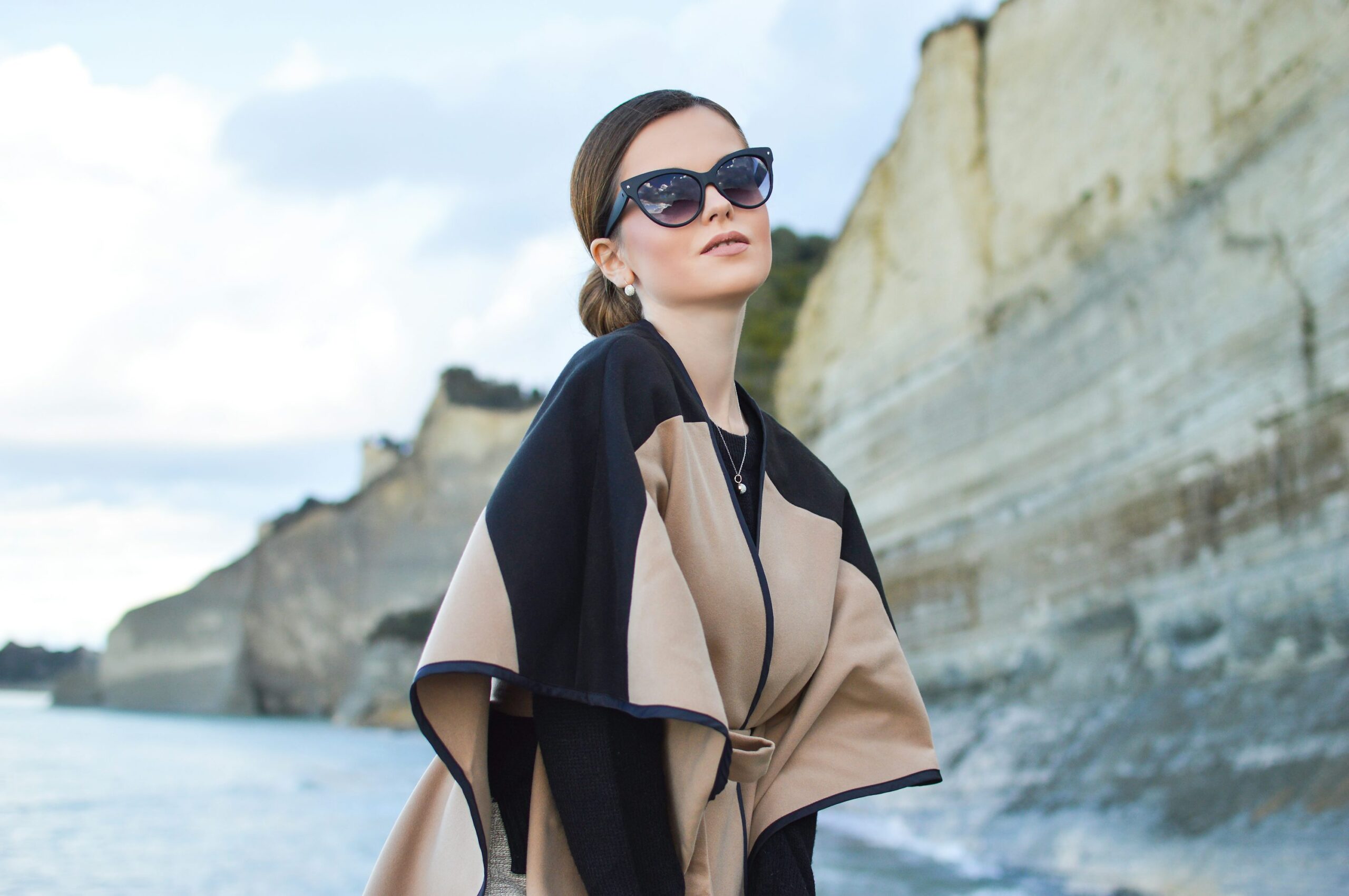 photo 1577909687863 91bb3ec12db5 - Magvilla woman wearing black and brown dress and sunglasses standing near body of water under white and blue sky